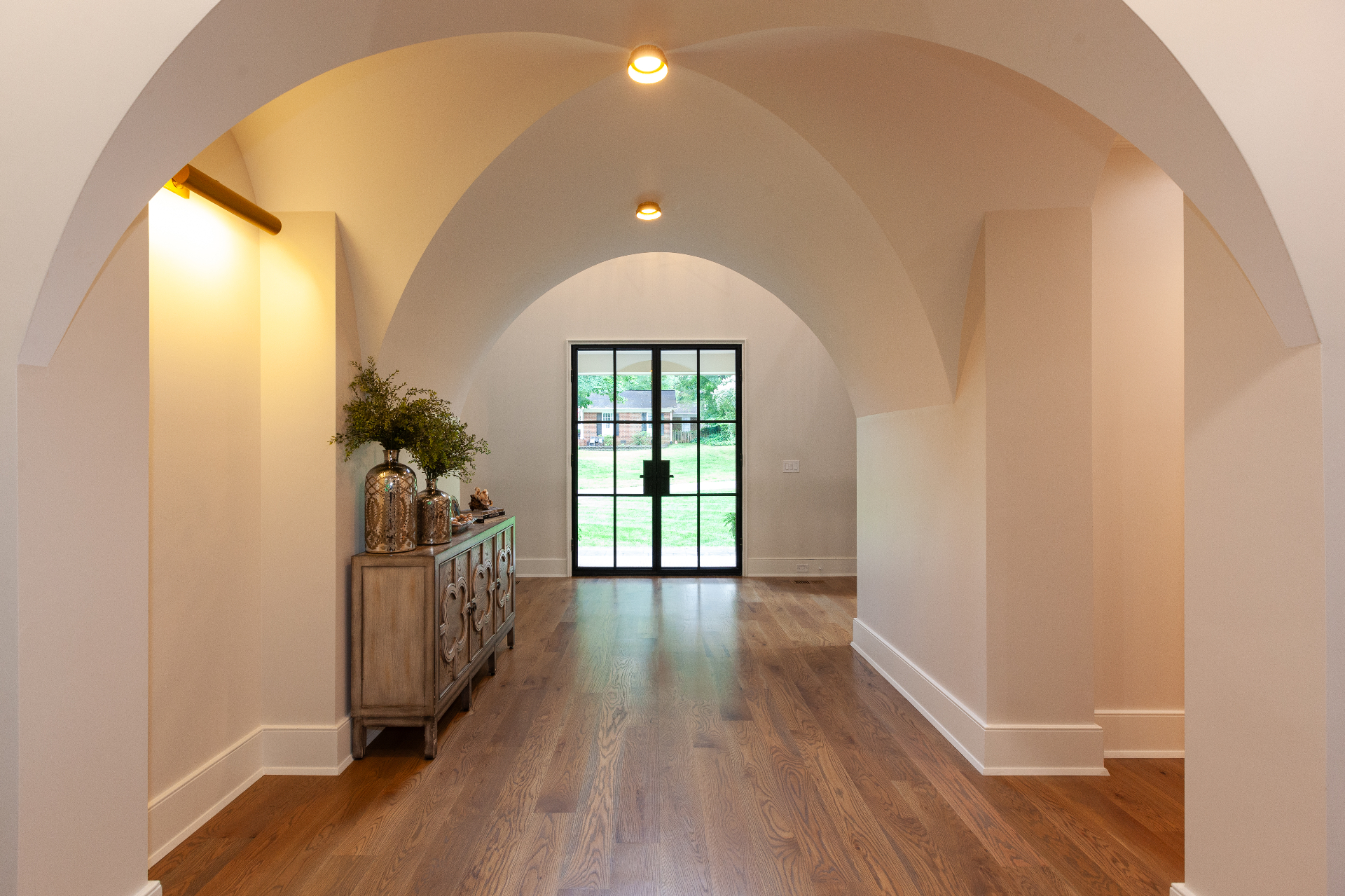 Interior hallway with barrel-vaulted ceilings, oak flooring, and steel-framed doors — a Bassett Homes residence